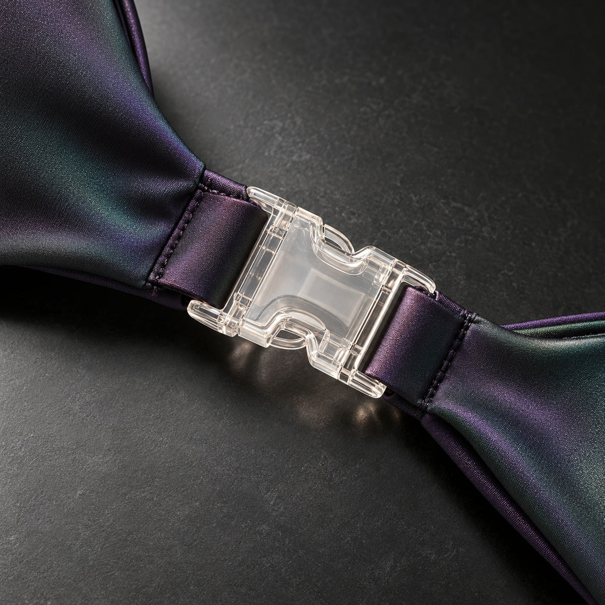 Macro of the transparent click closure on iridescent violet and green fabric